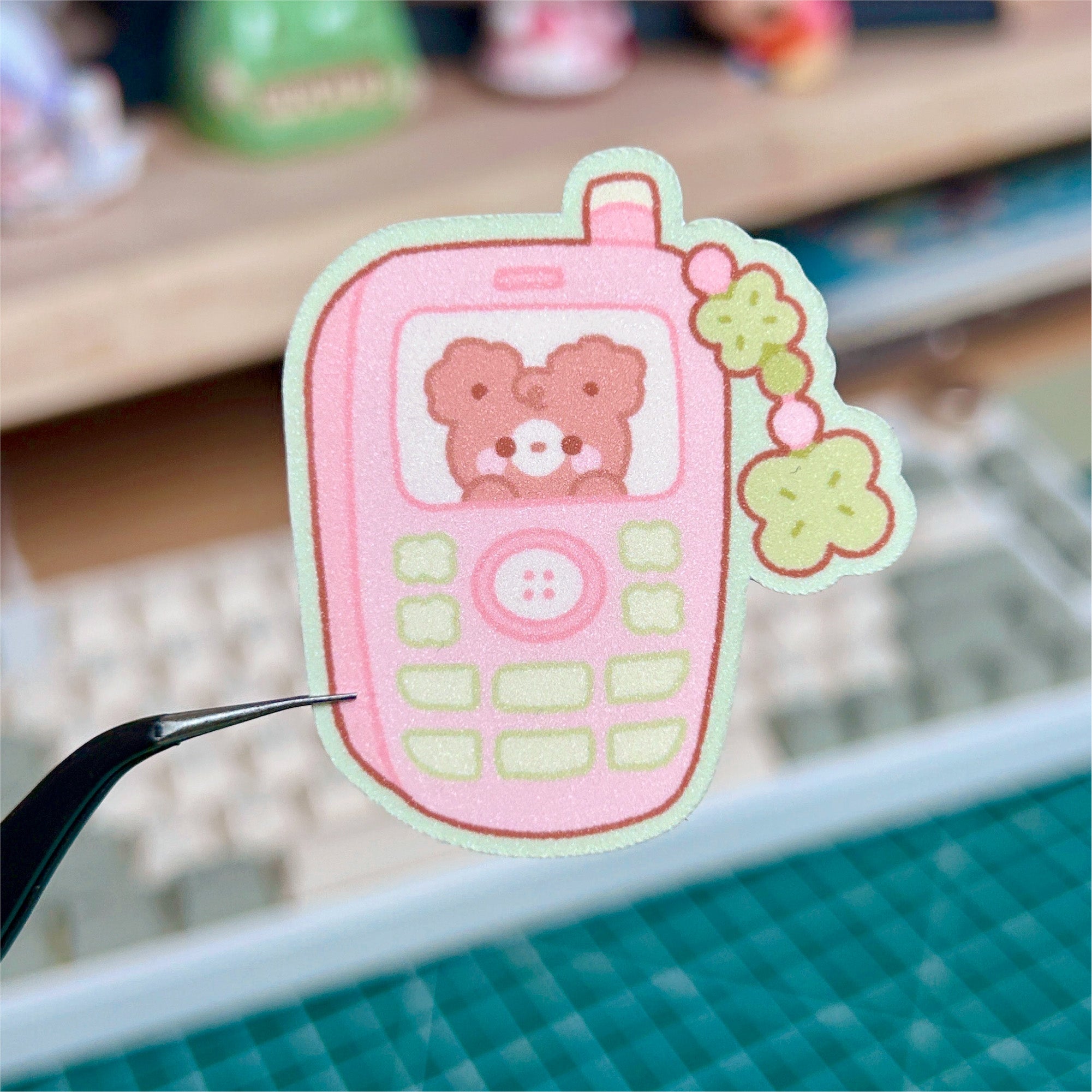 Pink cartoon phone sticker with a teddy bear on a cutting mat.