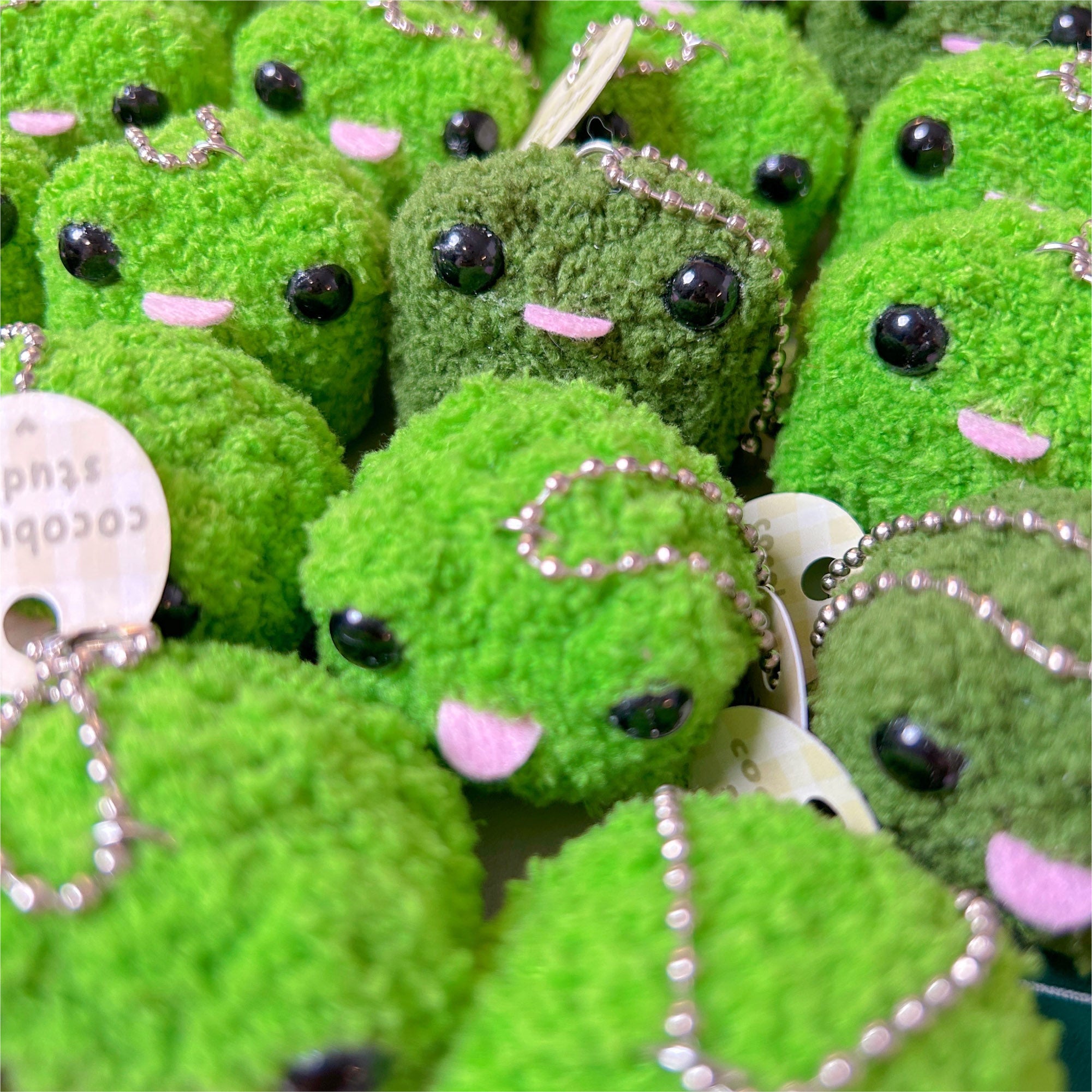 Green plush toys with black eyes and pink mouths.