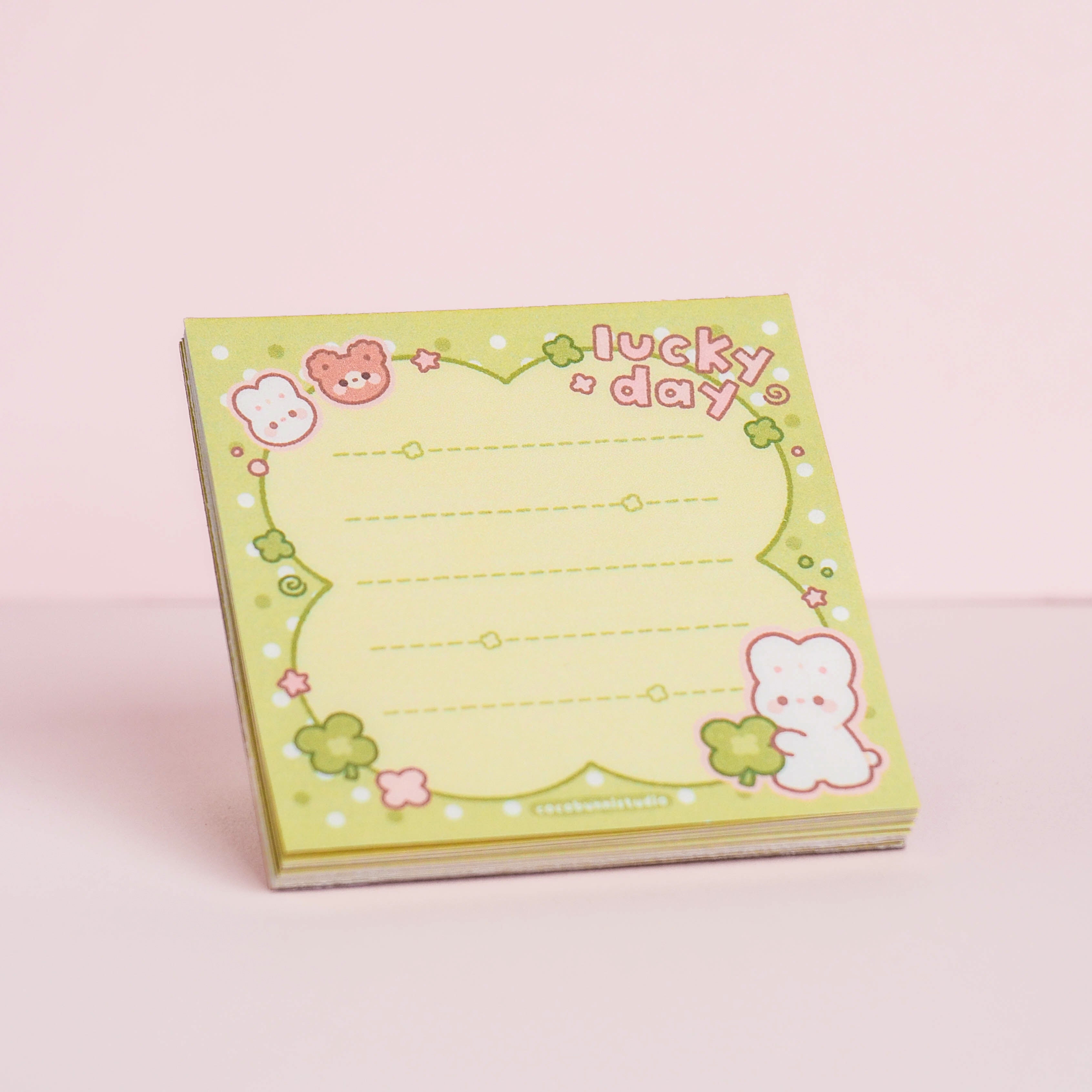 Notebook with characters and 'lucky day' text on a pink background
