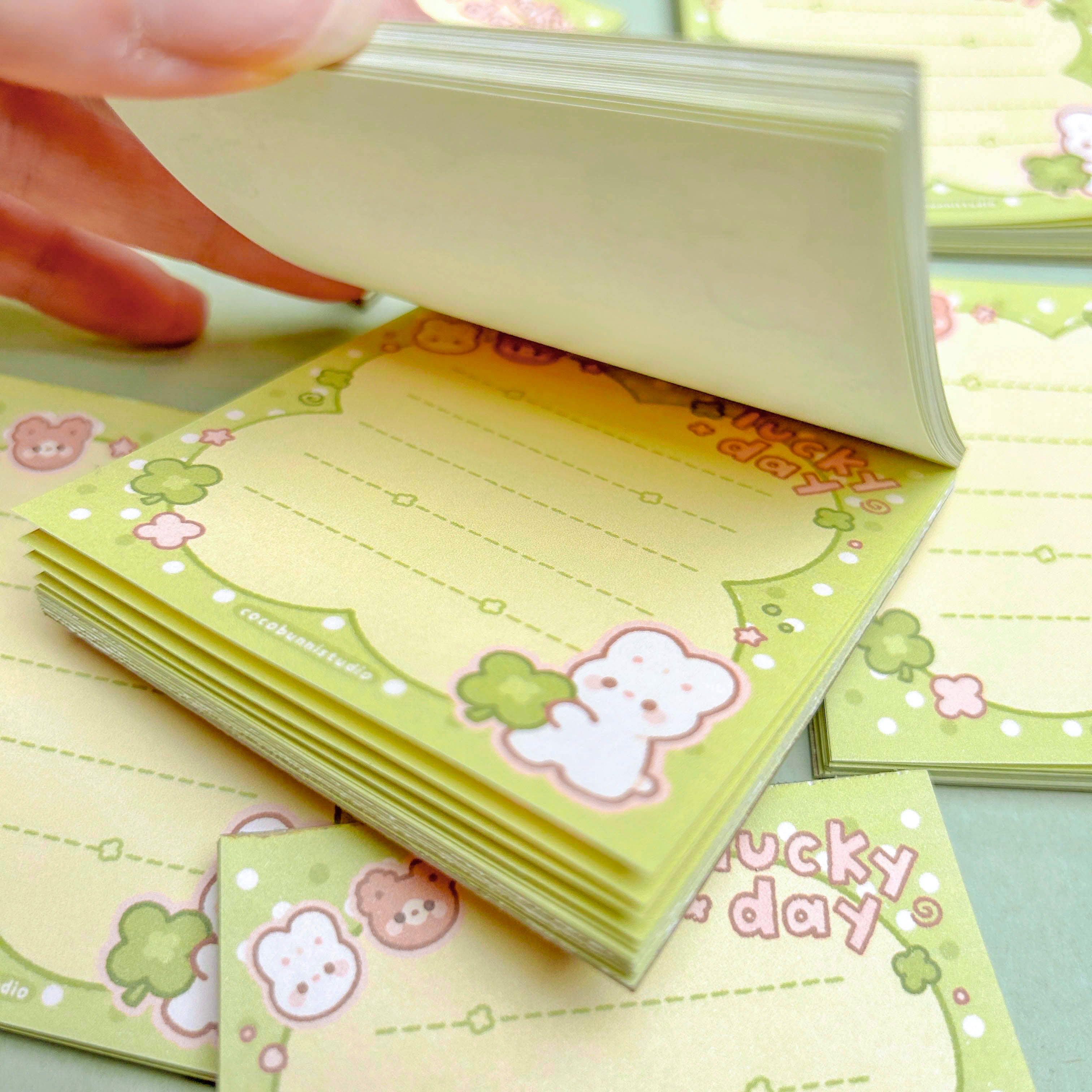Stack of small green notebooks with character designs and 'Lucky Day' text.