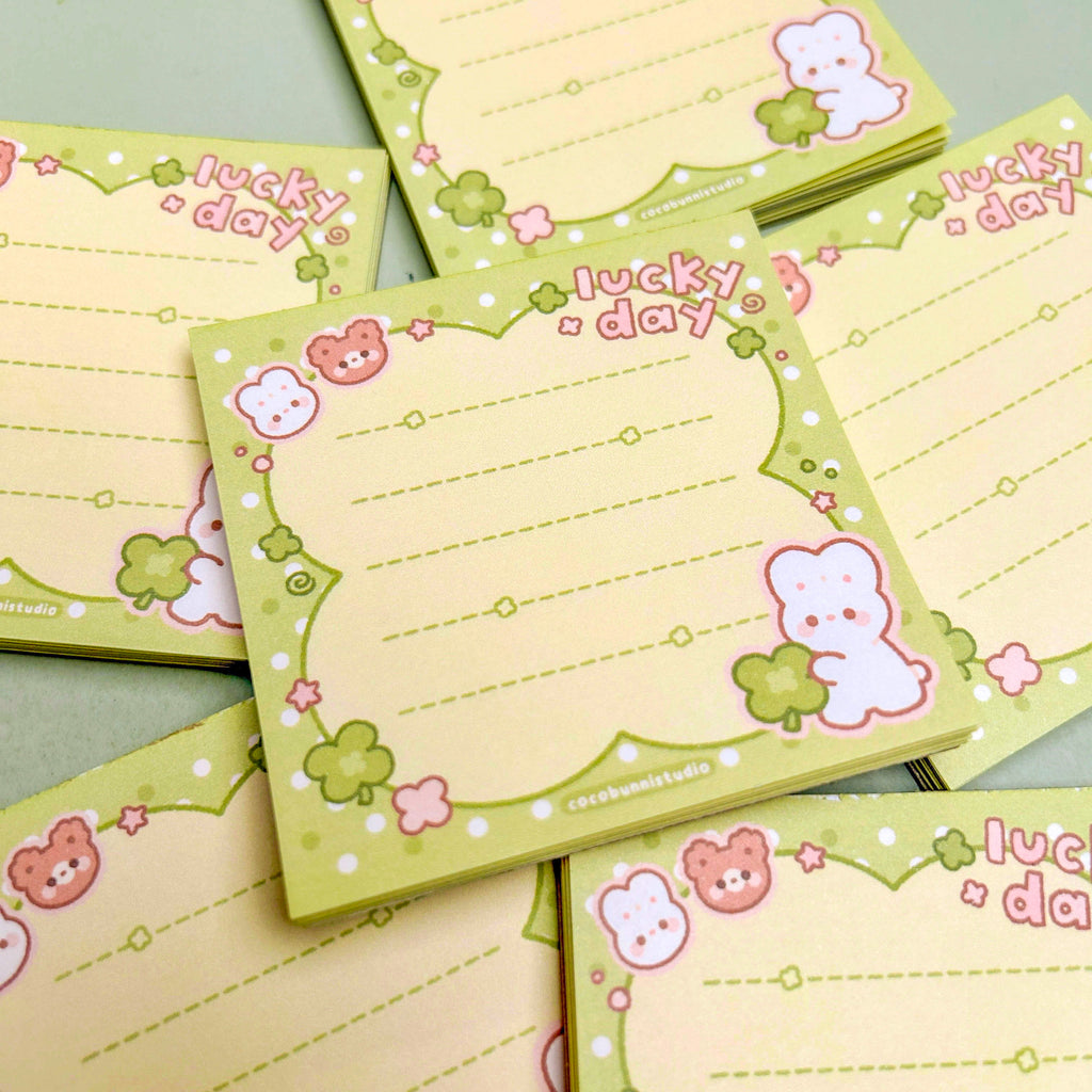 Set of small green notepads with cute character designs and 'lucky day' text on a light green background.