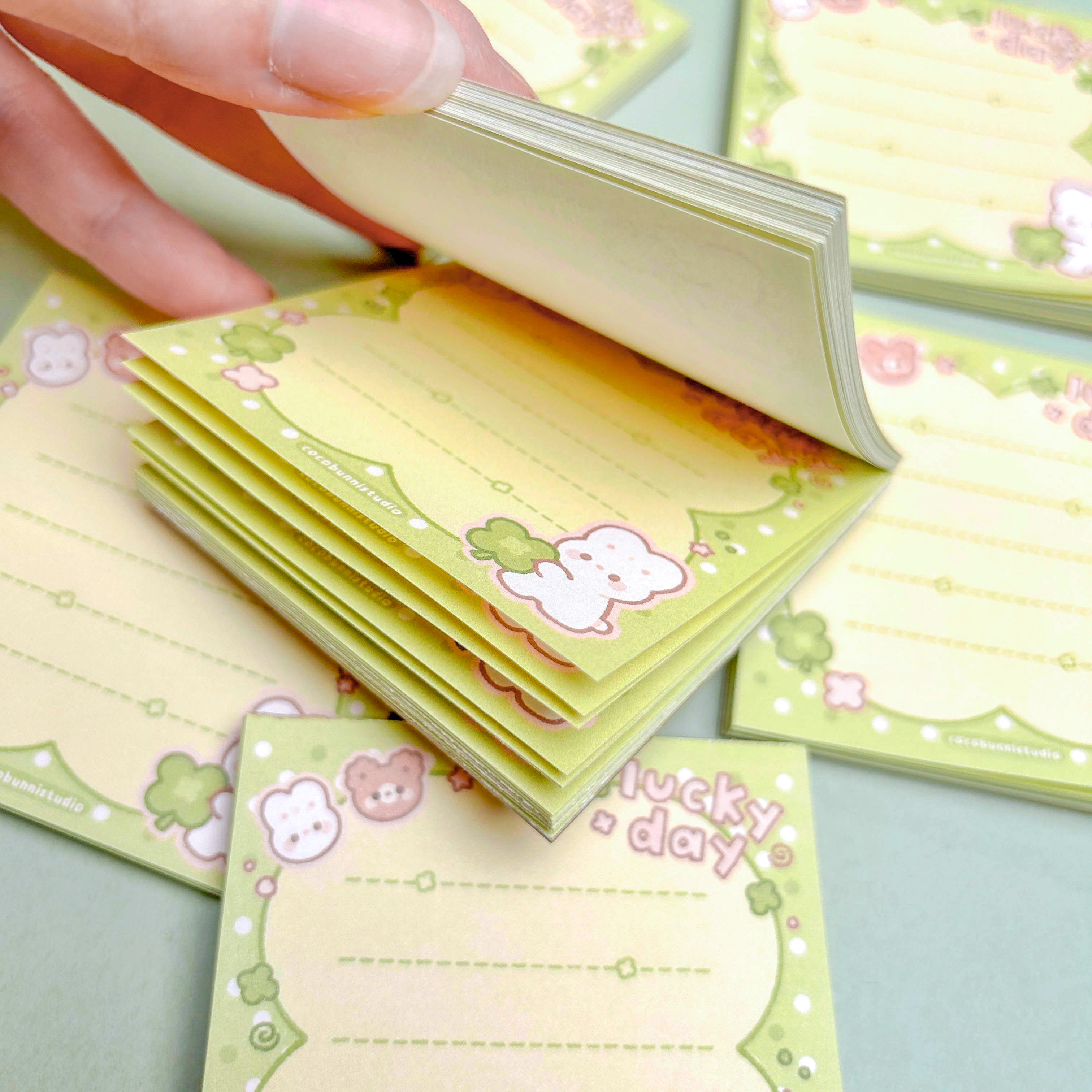 Stack of small green clover note pads on a light green background