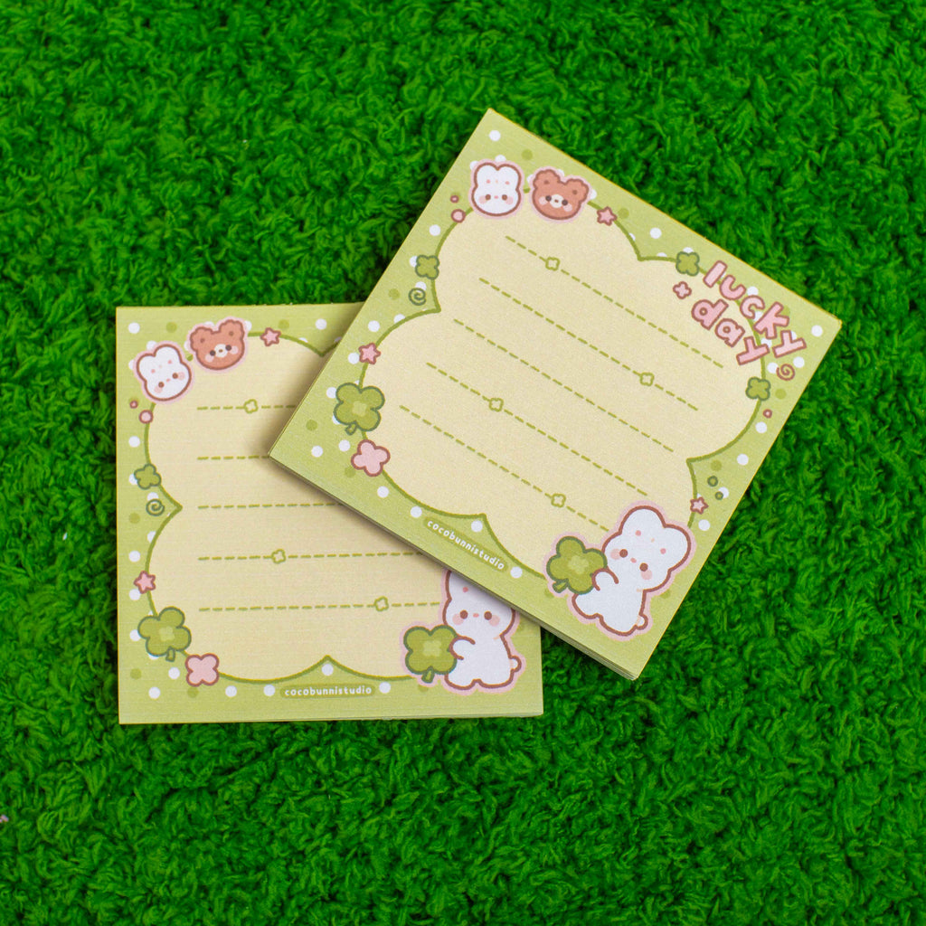 Two green notepads with cute characters on a grassy background