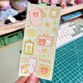 Sheet of cute stickers with cartoon characters held over a desk.