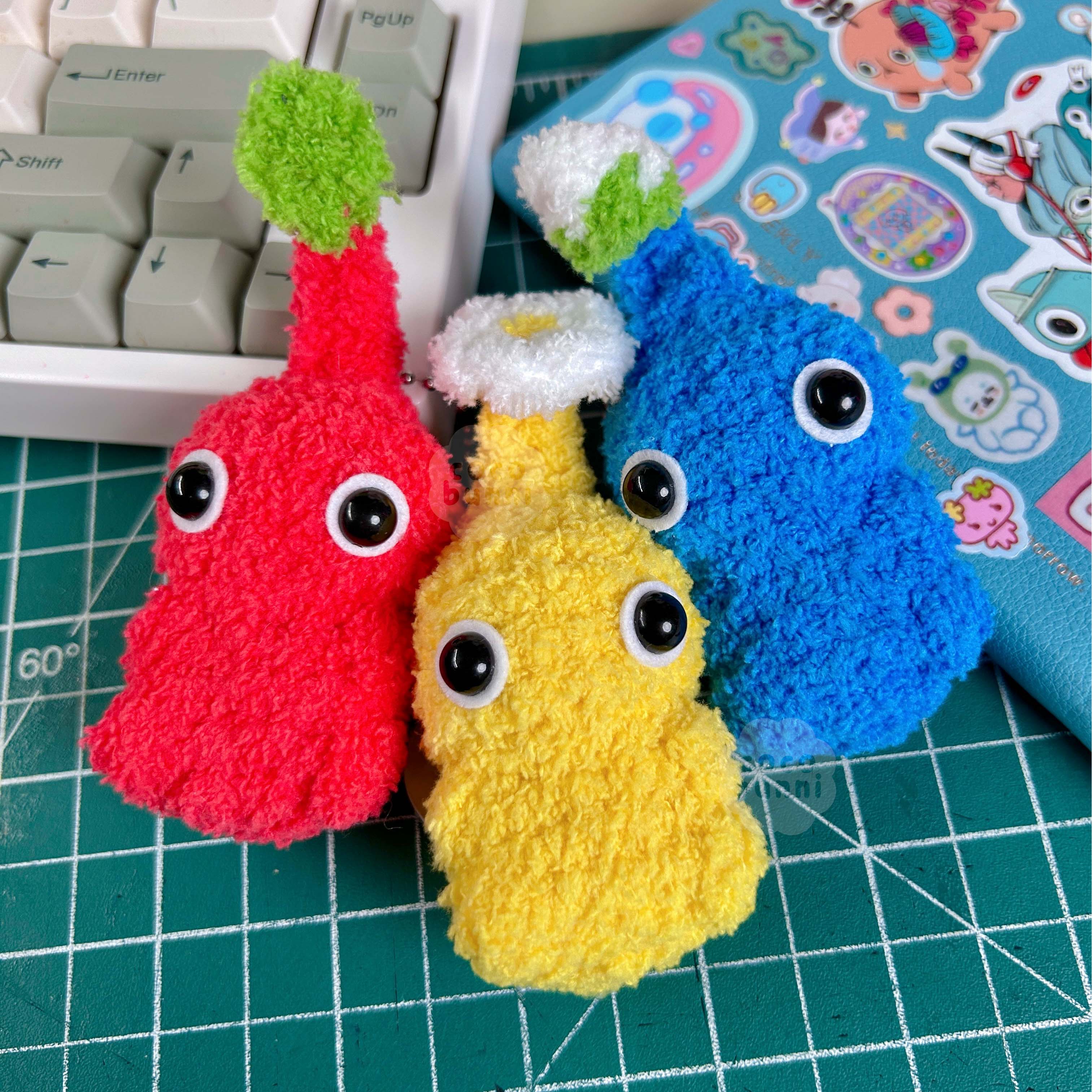 Three colorful plush toys on a green cutting mat.