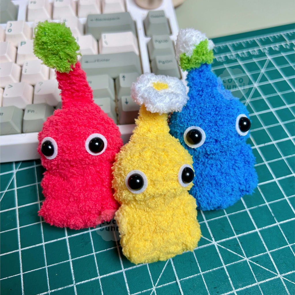 Three colorful plush toys on a cutting mat with a keyboard in the background.