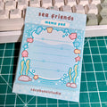 Memo pad with sea-themed design on a cutting mat with keyboard in the background