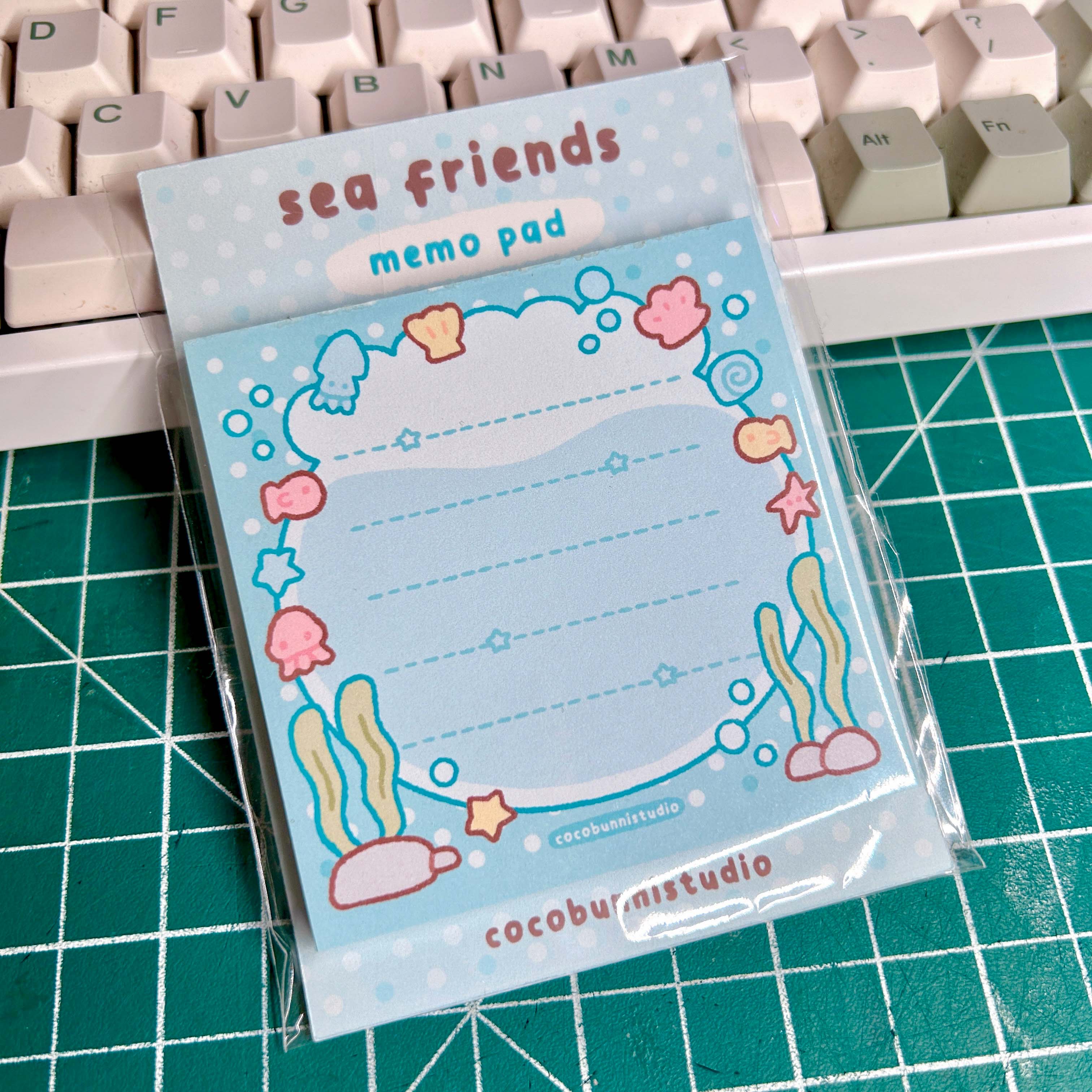 Memo pad with sea-themed design on a cutting mat with keyboard in the background