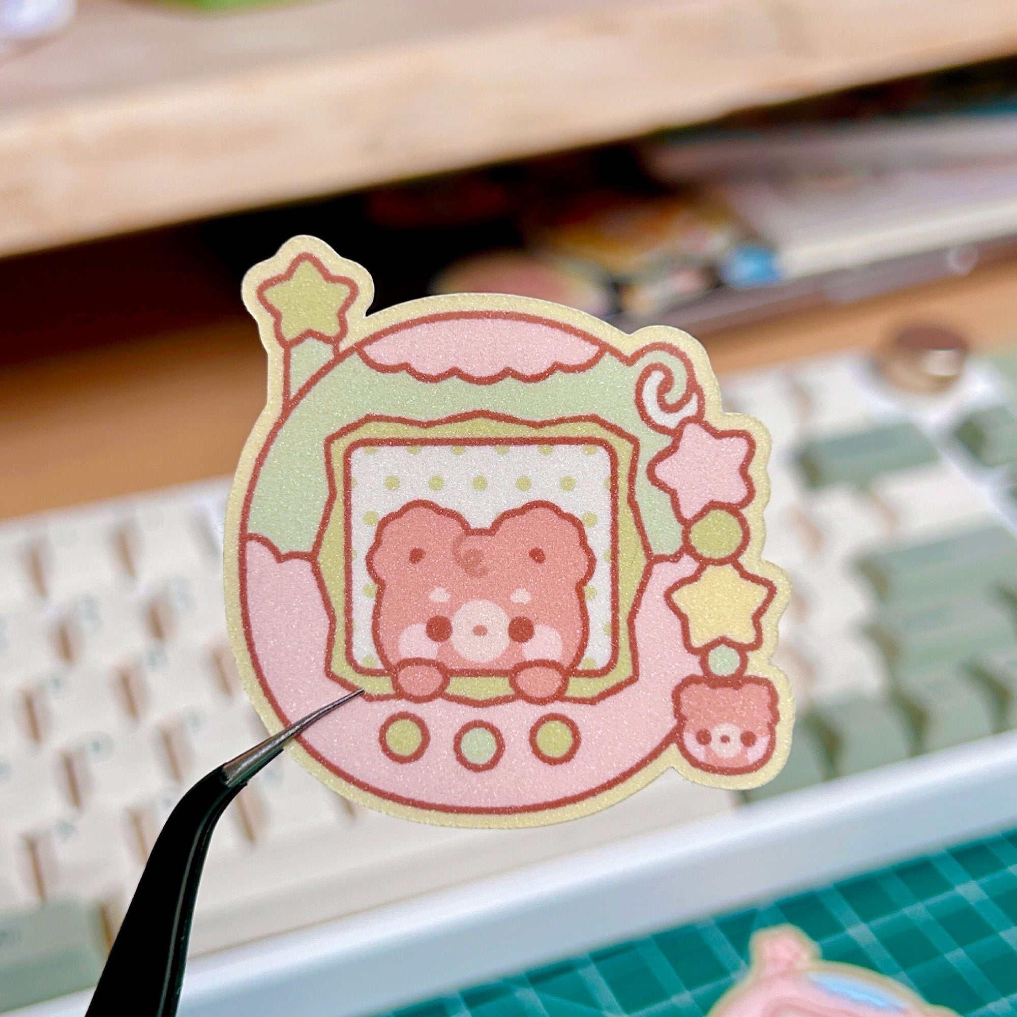 Cartoon bear sticker held by tweezers with a blurred background